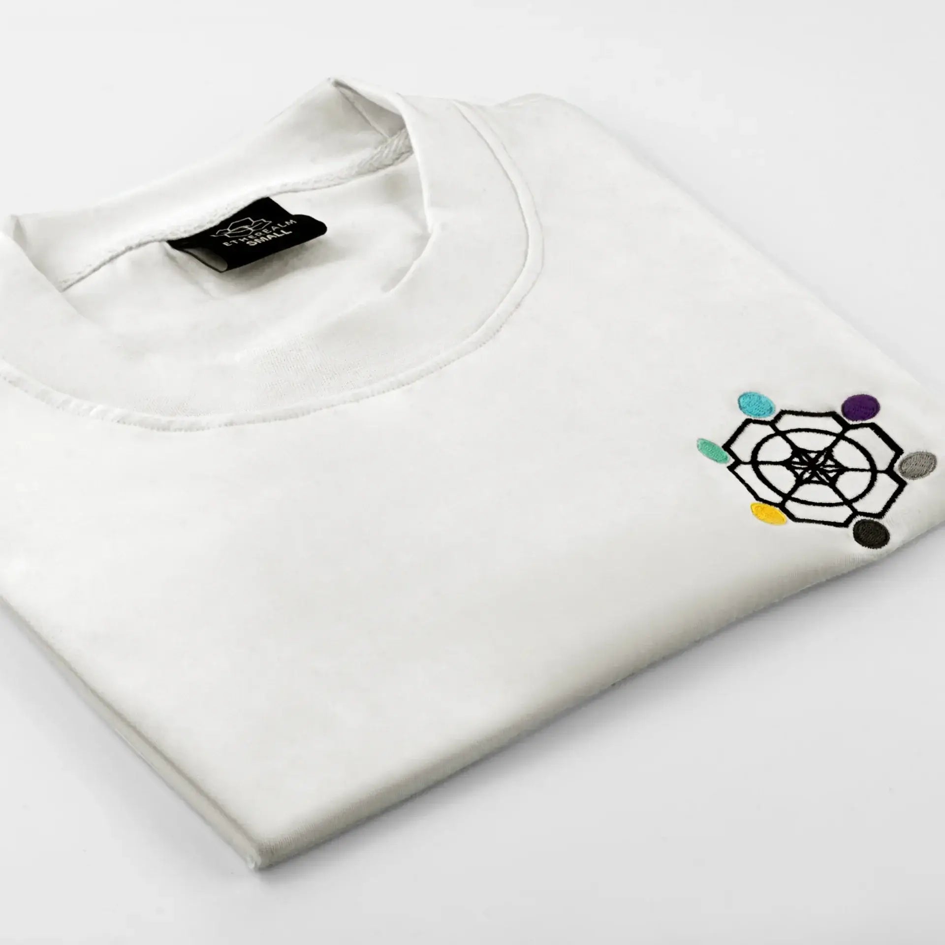 Elegant white ETHER TEE folded, featuring the Etherealm logo for stylish versatility.